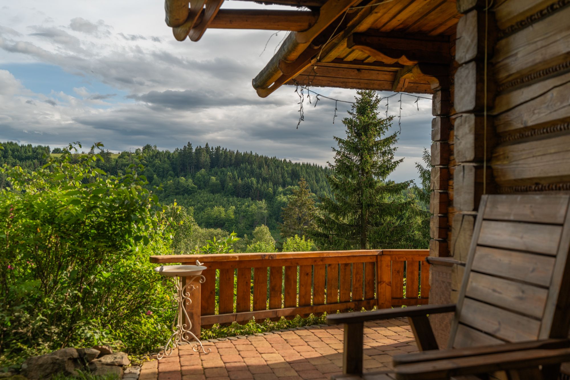 Krytá veranda roubenky s výhledem na zalesněné kopce